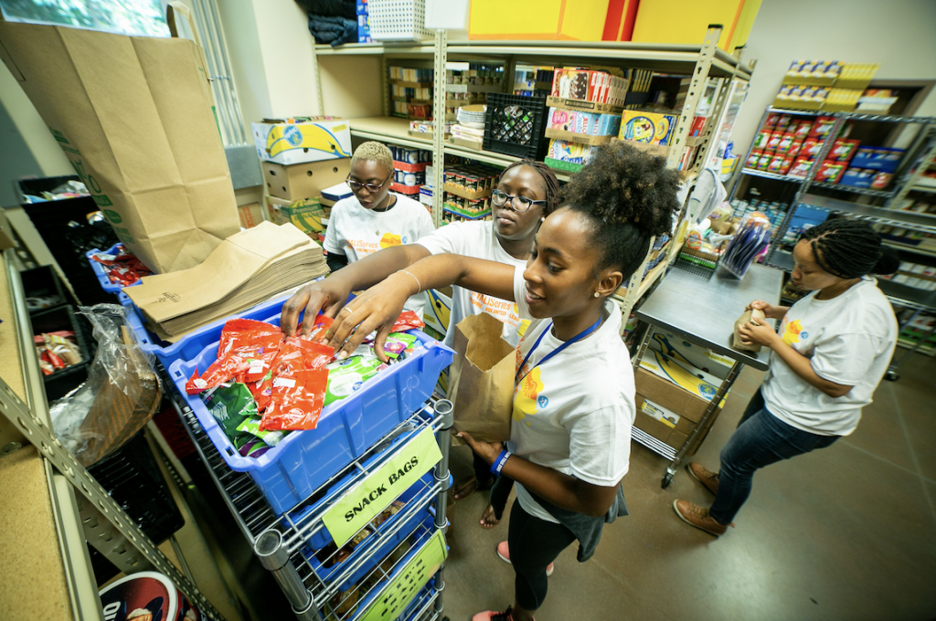 Mandela Fellows Doña Moleka, Nerima Were, and Maria Muadilu stock gift bags with snacks for local children.