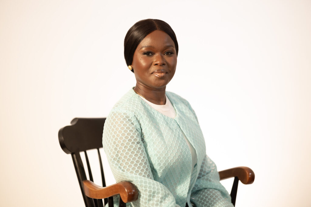 A woman seated in a chair with a plain white background