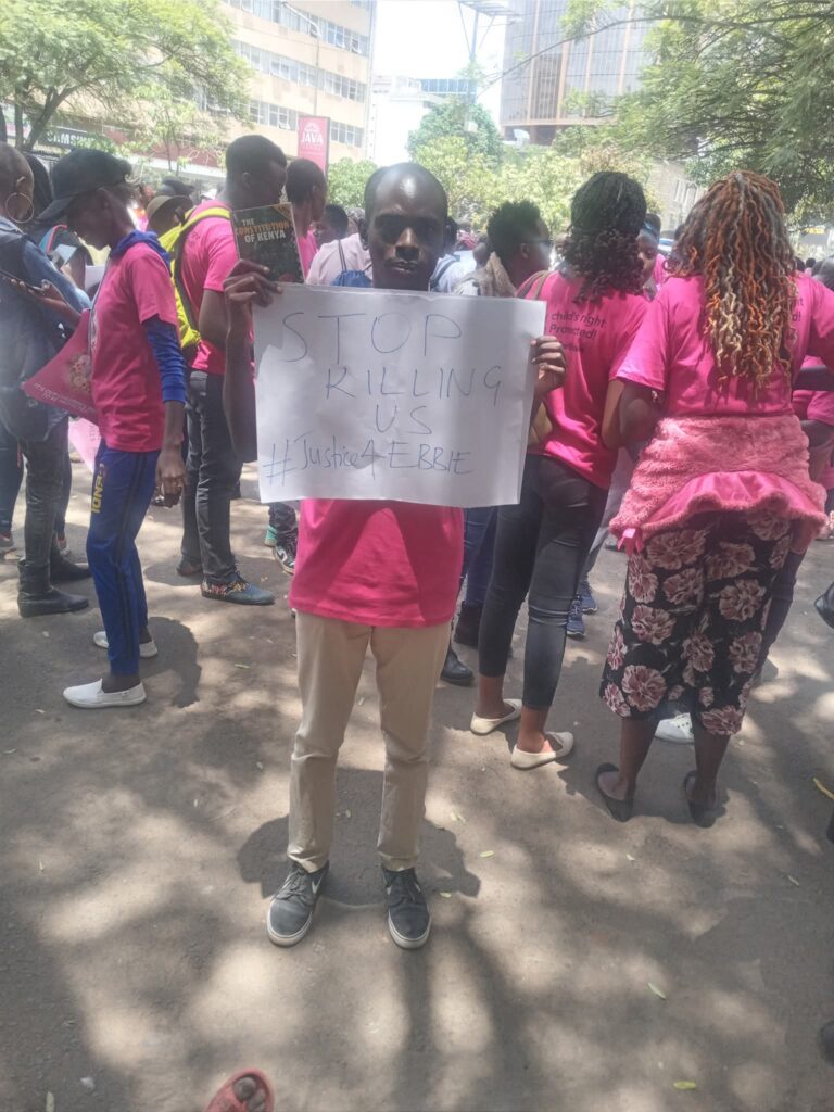 a young man in Kenya holds a sign that says "stop killing us"