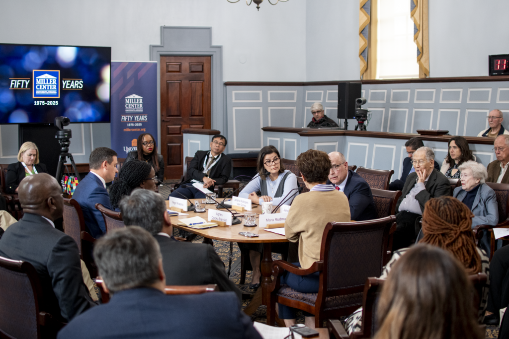group of people discuss around a table with an audience